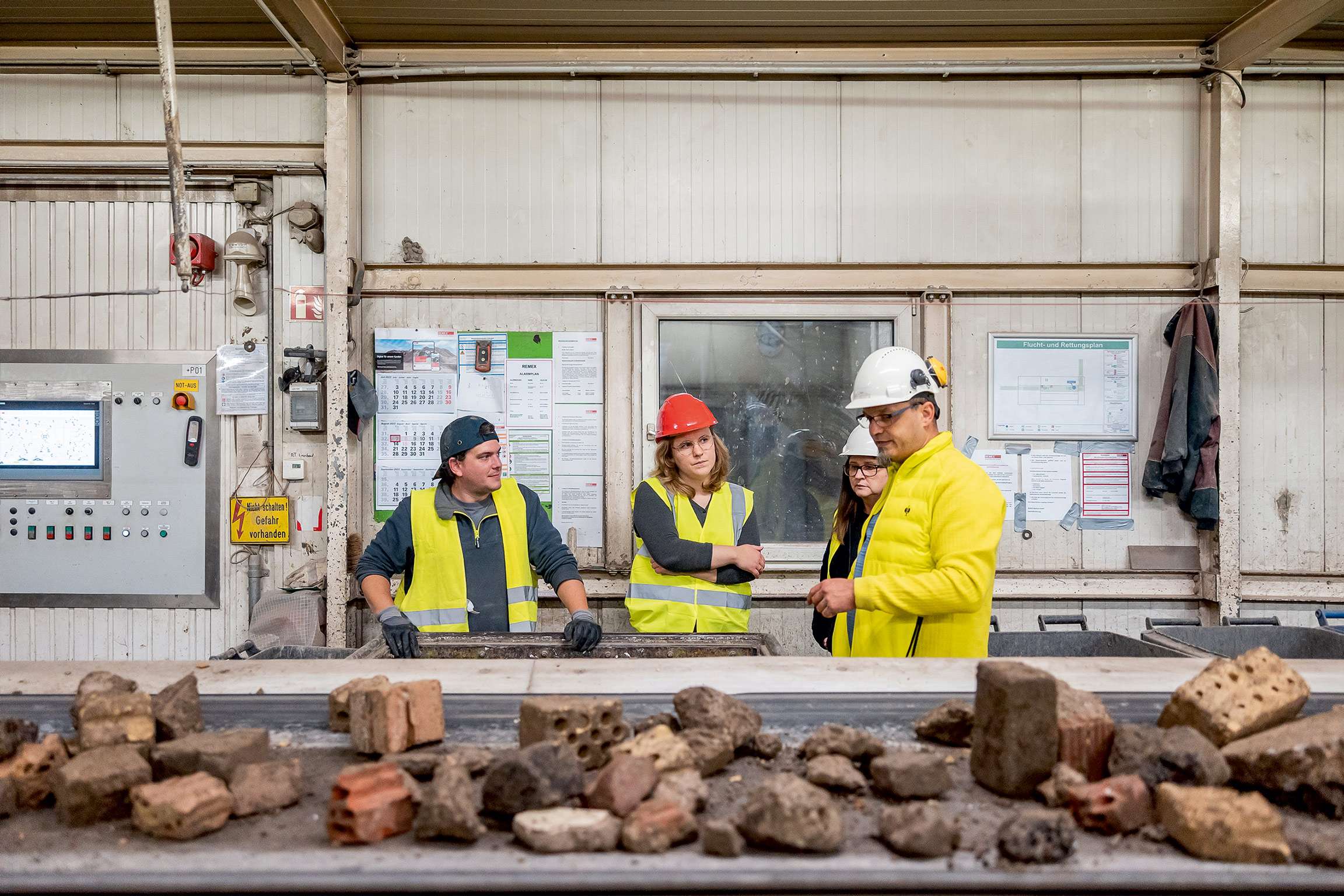 Bild von Roland Baege: VdW Mitarbeiter bei der Besichtigung der Anlage stehen vor einem Förderband