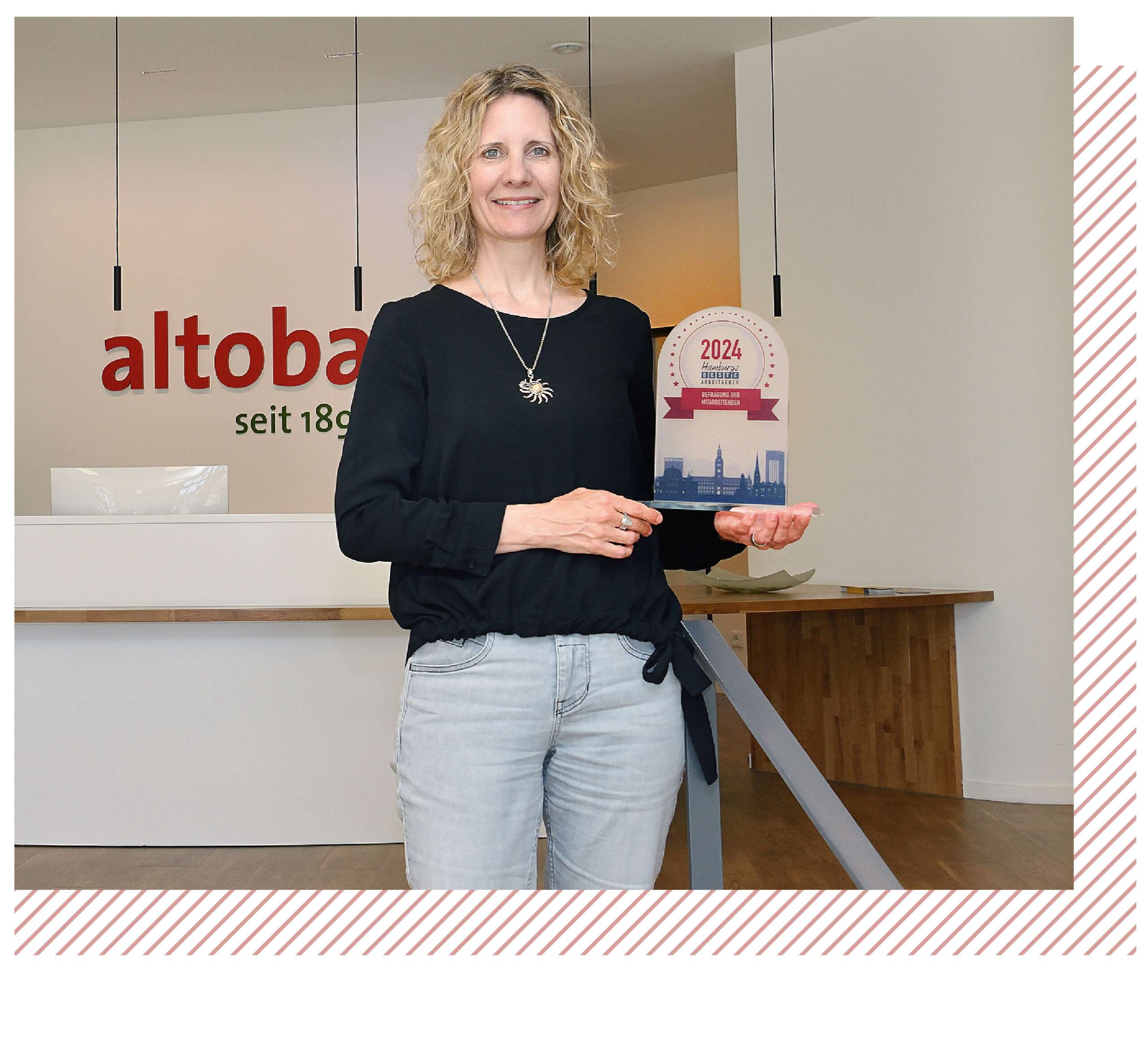 Bild von Ute de Vries in einem Bürogebäude, wie sie eine Auszeichnung in der Hand hält.